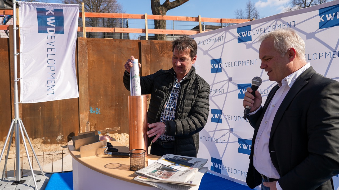 KW-Development Geschäftsführer Jan Kretzschmar (r.) erklärt, was alles in der Zeitkapsel enthalten ist, während Architekt Detlef Schöder die Kapsel befüllt. 